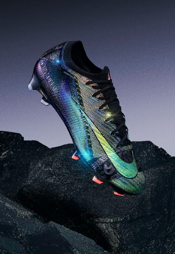 A Nike lançou a nova Air Zoom Mercurial 'Cosmic Speed', chuteiras em dourado e preto iridescente que destacam-se por seu design inovador e foco em velocidade. Parte da linha Mercurial, as novas Vapor XVI e Superfly X são usadas por jogadores como Vinícius Jr., Lauren James, Salma Paralluelo, e Sam Kerr, oferecendo um visual que muda de cor conforme o ângulo de visão. Utilizando a tecnologia PVD (Physical Vapor Deposition), o modelo celebra a agilidade no futebol e promete impactar tanto pelo estilo quanto pela performance em campo.