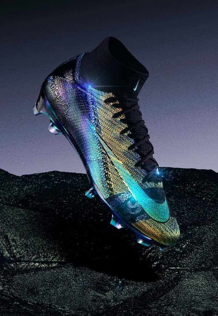 A Nike lançou a nova Air Zoom Mercurial 'Cosmic Speed', chuteiras em dourado e preto iridescente que destacam-se por seu design inovador e foco em velocidade. Parte da linha Mercurial, as novas Vapor XVI e Superfly X são usadas por jogadores como Vinícius Jr., Lauren James, Salma Paralluelo, e Sam Kerr, oferecendo um visual que muda de cor conforme o ângulo de visão. Utilizando a tecnologia PVD (Physical Vapor Deposition), o modelo celebra a agilidade no futebol e promete impactar tanto pelo estilo quanto pela performance em campo.